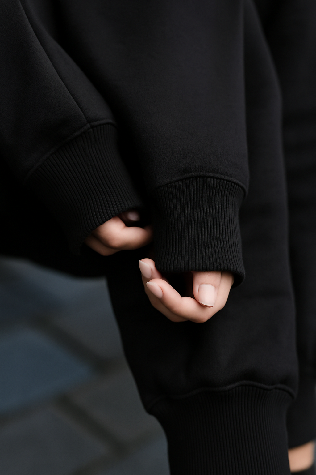 Person wearing a black hoodie with hands clasped together